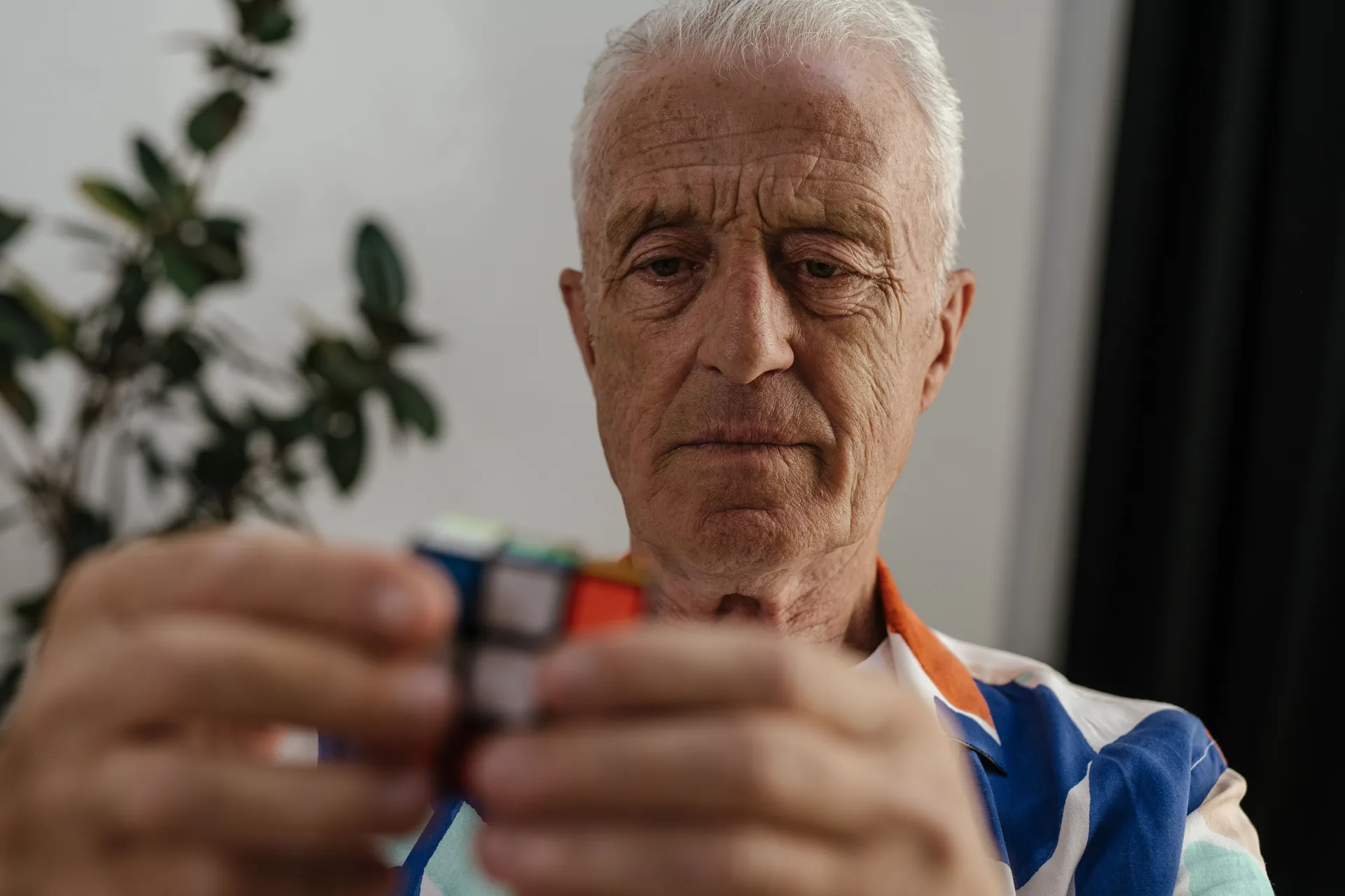 Hombre mayor concentrado resolviendo un cubo de Rubik en rehabilitación cognitiva